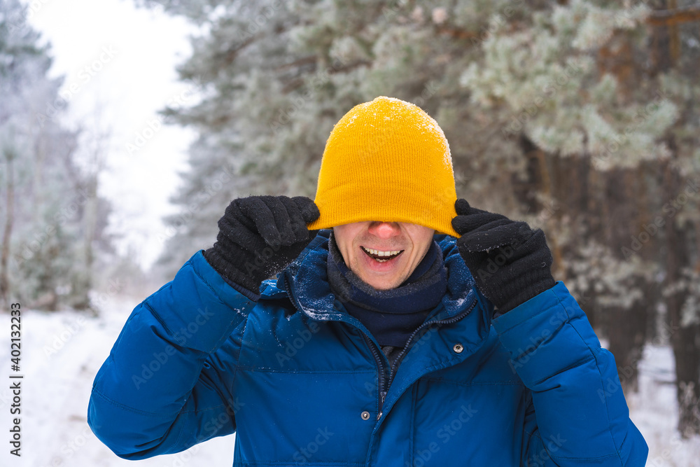 Smiling happy young man in winter jacket in snowy winter forest, Christmas vacation