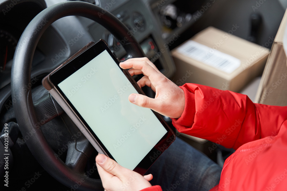 Delivery driver checking something at the tablet while sitting at the car