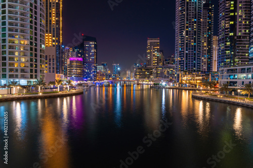 Night view to Dubai Marina panorama, reveals Pears 7, skyscrapers and beautiful bridge. Luxury destination for tourists and residents. Amazing colors reflect on the water. 