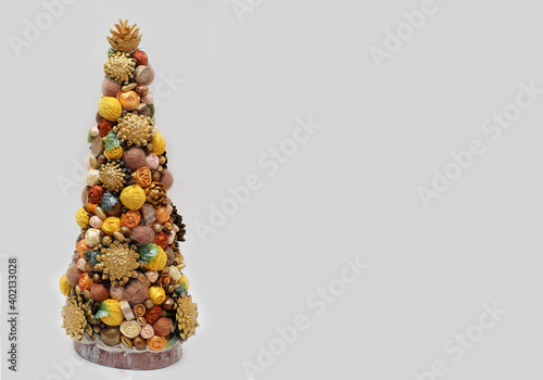 Handmade Christmas tree with pine cones, chestnuts and satin ribbons. Decor for the holiday. Free space for your text.