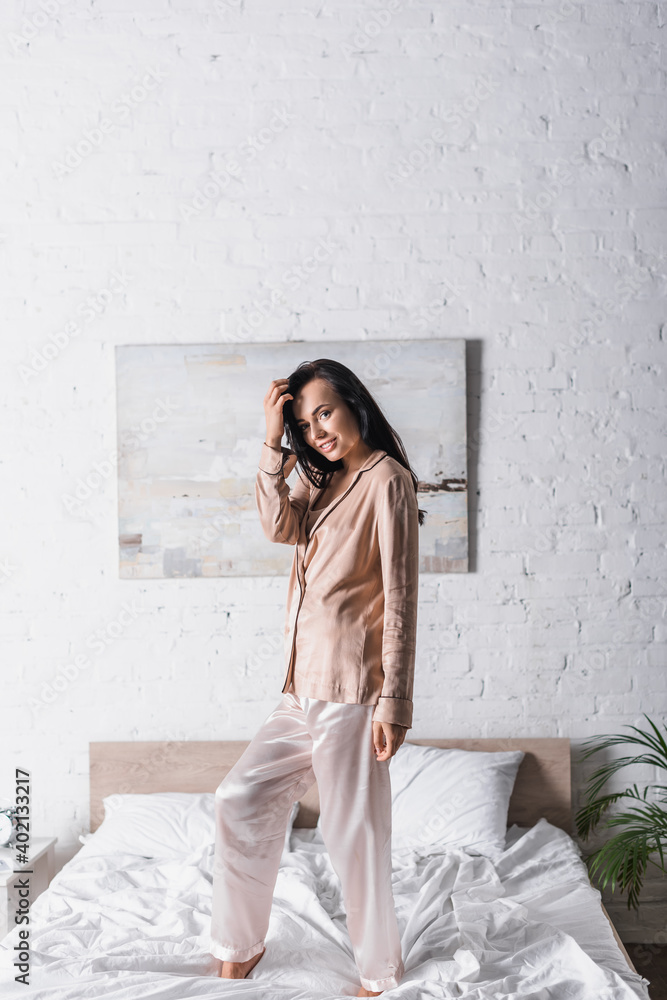 Fototapeta premium young woman standing on bed at morning