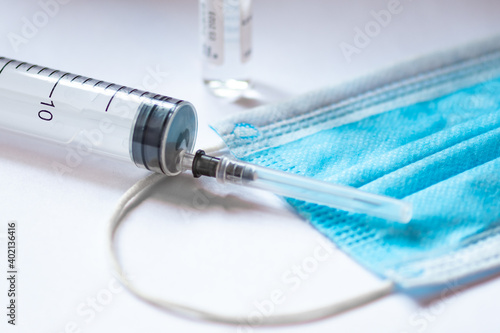Syringe, vial and surgical face mask on a white table. Covid or Coronavirus vaccine background photo