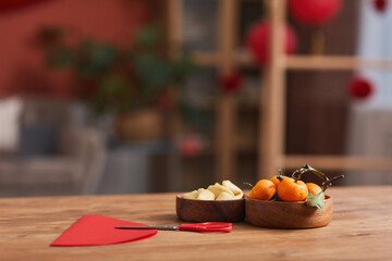 Conceptual no people shot of tangerines, fortune cookies and colored paper on table in living room decorated for Chinese New Year Celebration