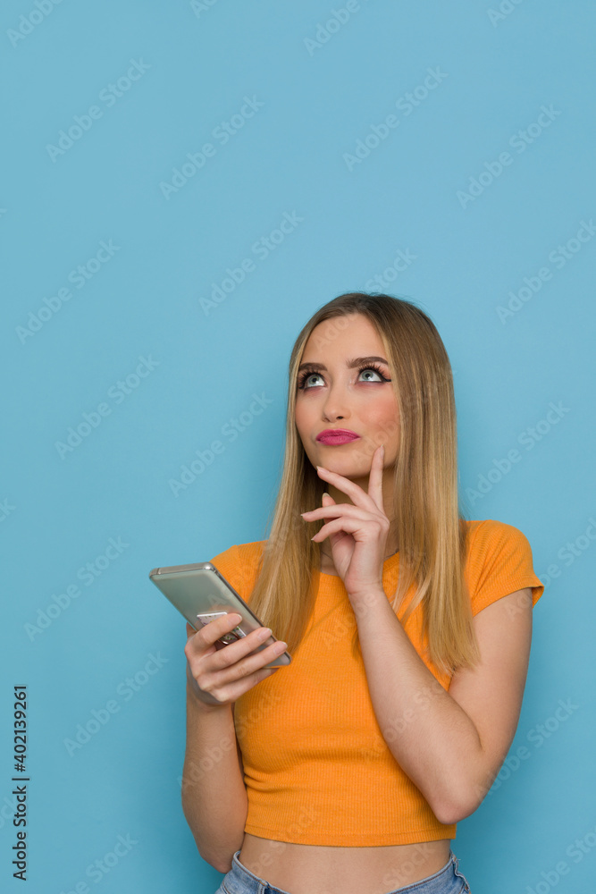 Young Woman Is Holding Telephone, Looking Up And Thinking Young Woman Is Holding Telephone, Looking Up And Thinking