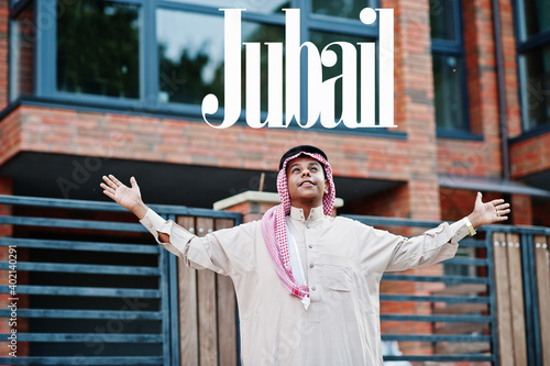Jubail - biggest city of Saudi Arabia. Middle Eastern saudi arabian man posed on street against modern building up his hands in the air. photo