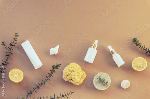 Cosmetic oil, serum and organic soap. Eco-friendly spa, massage, peeling and hydration products. Beige background, lemon fruits and eucalyptus leaves. Top view, flat lay, copy space.