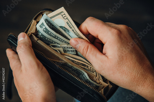 An empty wallet with a small amount of money in the hands of a working man. Poverty concept