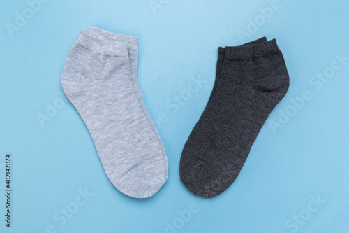 two pairs of multicolored new socks stacked on a blue background. top view. © Nana_studio