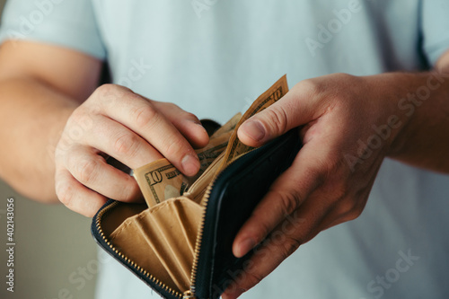 wallet with small paper dollar bills in a wallet in the hands of a bankrupt man. Poverty concept, crisis. dismissal