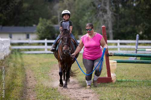 child riding a pony with an instructor © Daniel Teetor