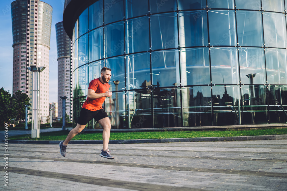 Fast sportsman running in city near glass building