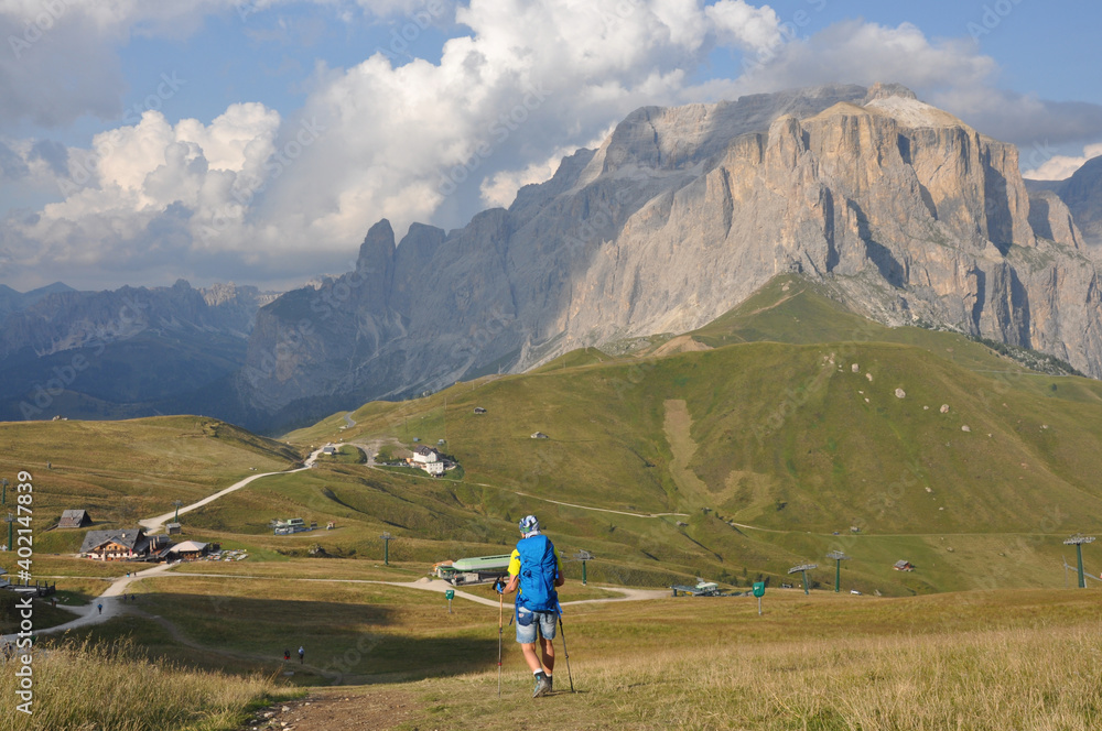 Kobieta schodzi łąką z górskim łańcuchem w tle, Dolomity, Włochy