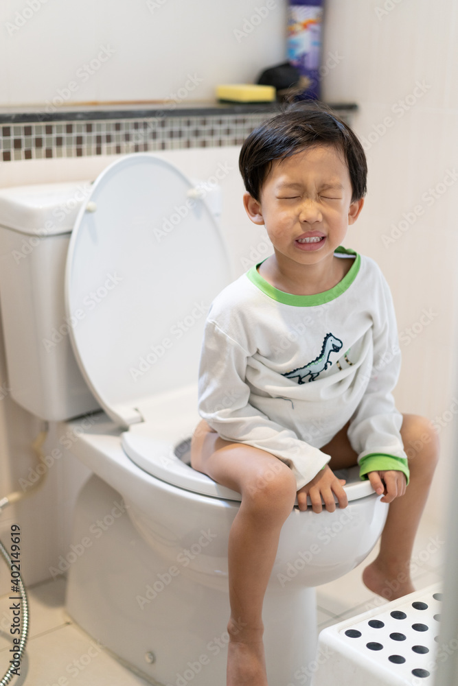 A boy is sitting on toilet with suffering. A boy is sitting on toilet with suffering.
