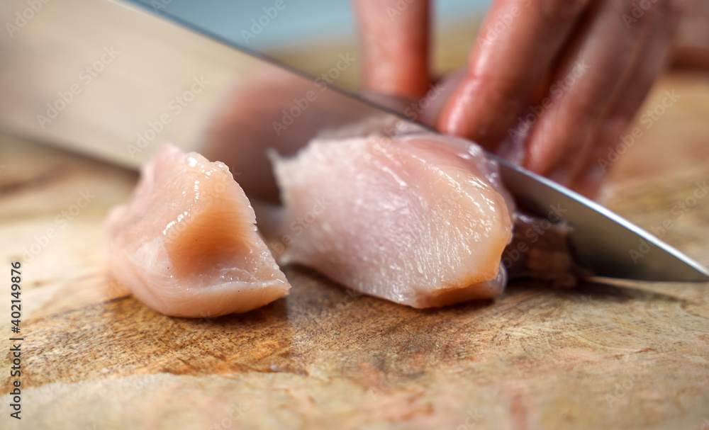 Woman is cutting chicken fillet with a knife. Woman is cutting chicken fillet with a knife.