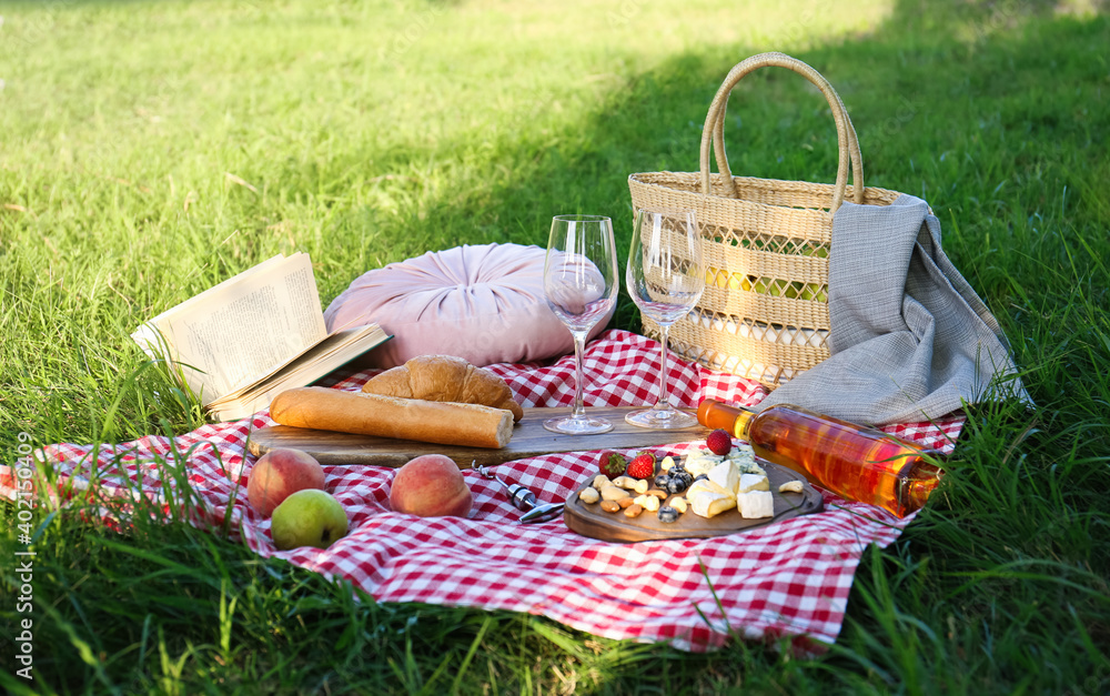 Picnic blanket with delicious food and wine on green grass in park Picnic blanket with delicious food and wine on green grass in park
