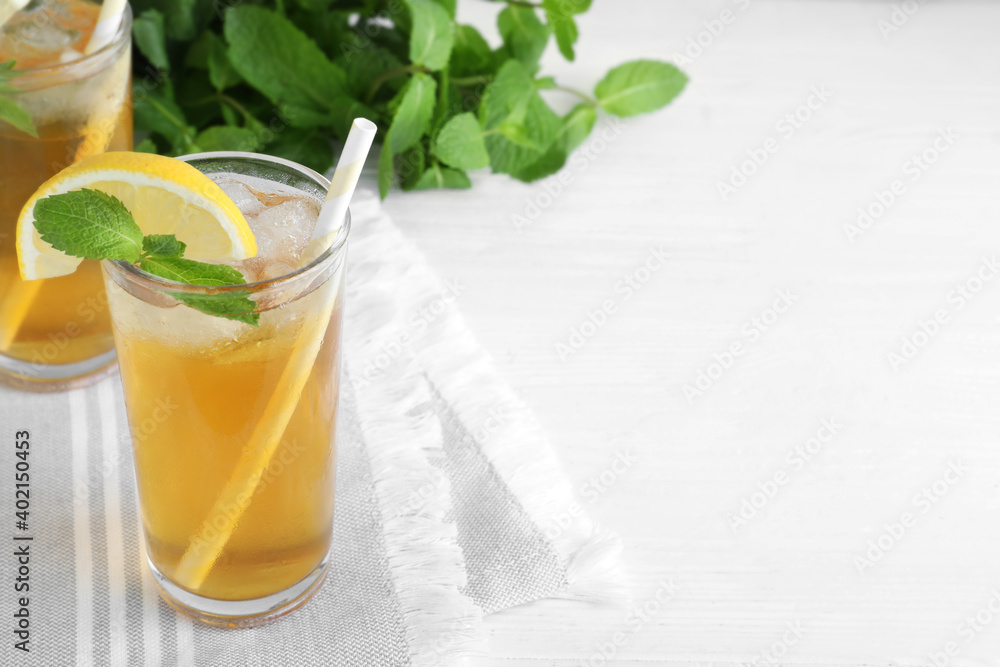 Delicious iced tea with lemon and mint on white wooden table. Space for text Delicious iced tea with lemon and mint on white wooden table. Space for text