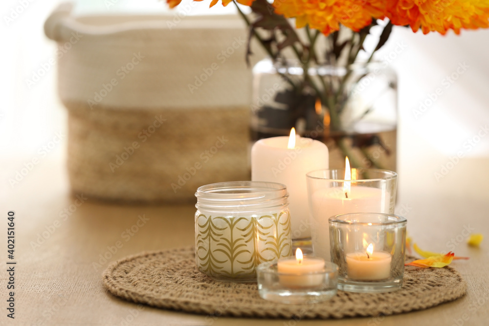 Beautiful burning candles, bag and flowers on table at home Beautiful burning candles, bag and flowers on table at home