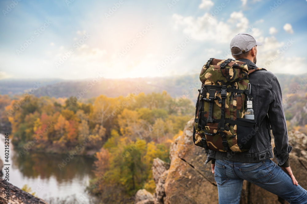 Fototapeta premium Traveler with backpack enjoying beautiful view near mountain river. Autumn vacation