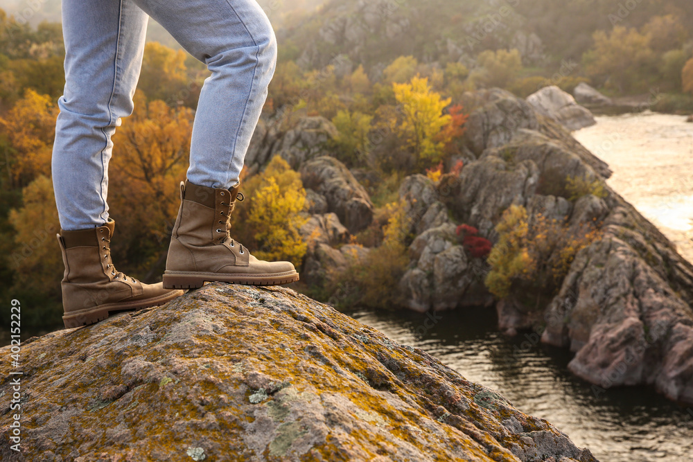 Woman wearing stylish hiking boots on steep cliff, closeup Woman wearing stylish hiking boots on steep cliff, closeup
