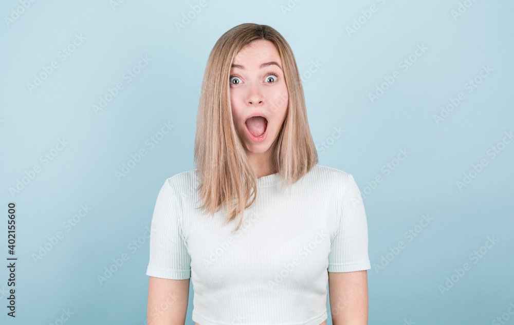 Image of an excited screaming young woman standing isolated on a blue background. Looking camera. Image of an excited screaming young woman standing isolated on a blue background. Looking camera.