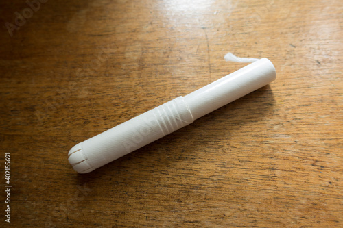 1 tampon with cardboard applicator on wooden table