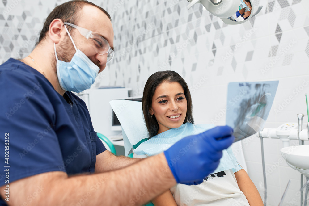 Obraz premium people, medicine, stomatology and health care concept - happy male dentist showing work plan to woman patient at dental clinic office