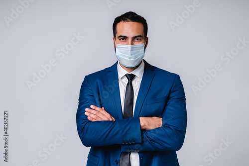 Attractive confident islamic businessman in medical mask against coronavirus isolated over grey background