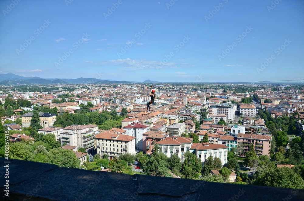 View from the city wall of Bergamo Upper Town towards the Lower Town, a person on a zip wire drive, summer