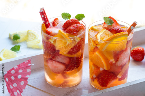 Zwei Gläser selbstgemachte frische sommerliche Limonade aus Erdbeeren und Orange stehen auf einem weißen Holztablett