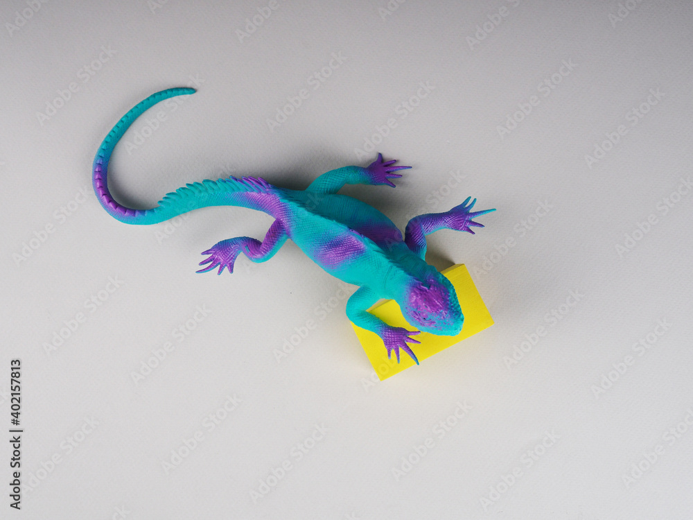 Fototapeta premium toy iguana lizard on a gray and yellow background, concept photo, space for text