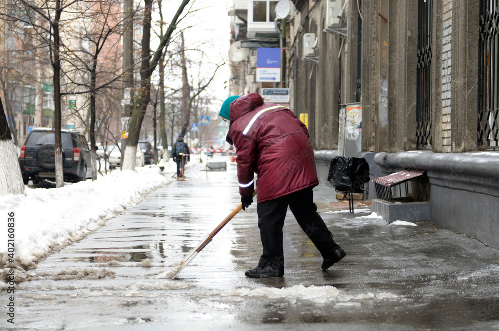 Municipal worker removing snow and ice from streets of city after blizzard Municipal worker removing snow and ice from streets of city after blizzard