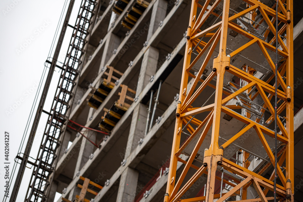 Obraz premium Yellow construction crane attached to the wall of an office building under construction