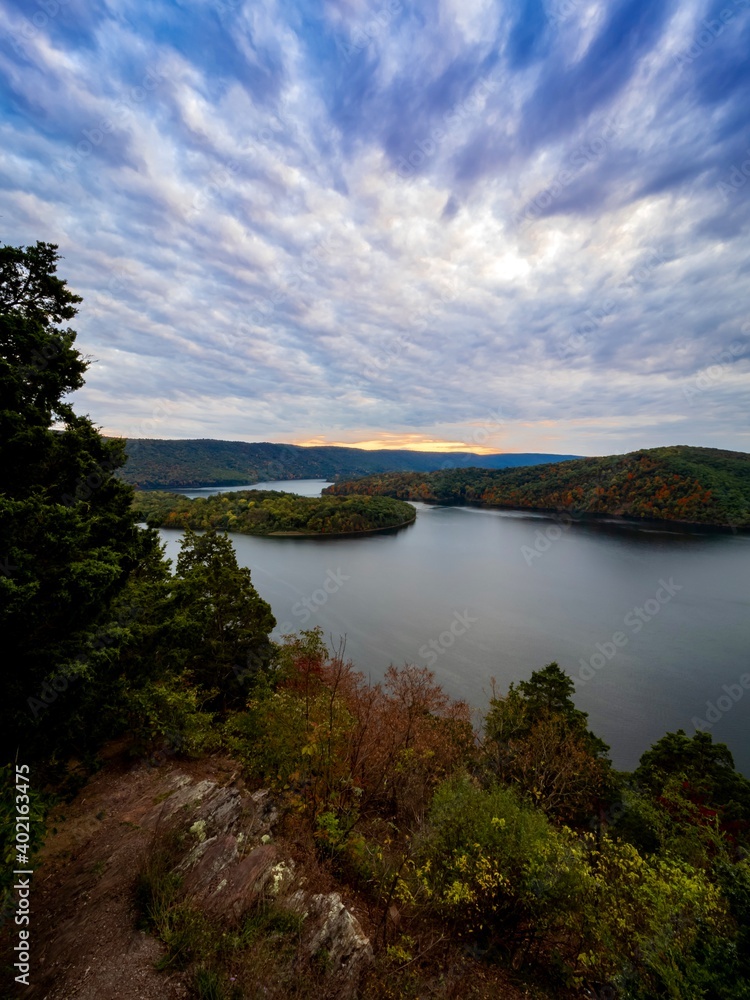 Hawn’s Overlook of Raystown Lake in the mountains of Pennsylvania in the fall right before sunset with a dramatic blue swirly sky with orange tones in it and water as smooth as glass.