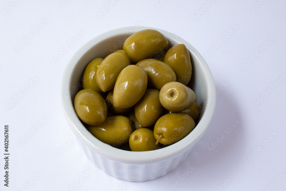 Pickled green olives in white bowl on white background Pickled green olives in white bowl on white background