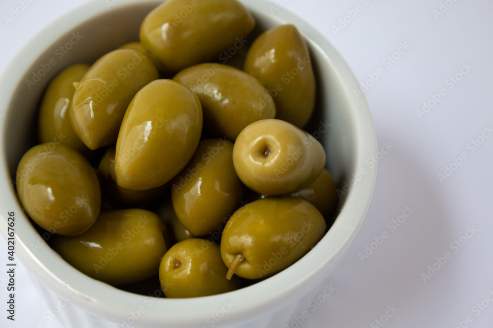 Pickled green olives in white bowl on white background Pickled green olives in white bowl on white background