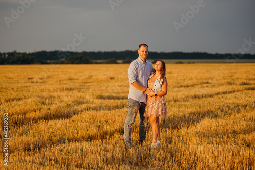 A happy couple in a field in the rays of the setting sun