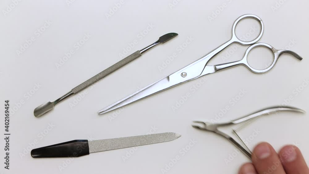 A man in close-up takes scissors, nippers, scraper and nail file. Demonstration of tools for manicure. Items for work on a light surface. Professional hand care. Isolated video on a white background. A man in close-up takes scissors, nippers, scraper and nail file. Demonstration of tools for manicure. Items for work on a light surface. Professional hand care. Isolated video on a white background.