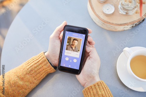 Close-up of man using his mobile phone for online dating while sitting at the table