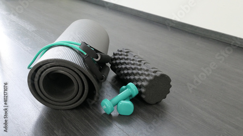 equipment in gym - green dumbbells theraband a gym mat and a fascias roll on a dark background  photo