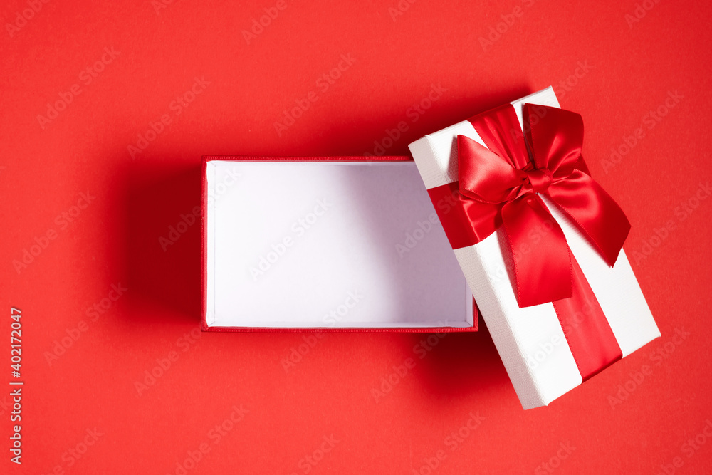 White open gift box with red bow on red background. Valentine day, birthday, Christmas, concept, design. Flat lay, top view, copy space White open gift box with red bow on red background. Valentine day, birthday, Christmas, concept, design. Flat lay, top view, copy space