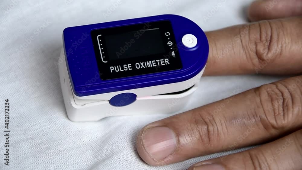 A man put on a pulse oximeter on his finger and checks his heart rate and the amount of oxygen in his blood. A man put on a pulse oximeter on his finger and checks his heart rate and the amount of oxygen in his blood.