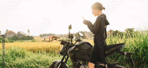 Serious young woman sitting on bike and browsing