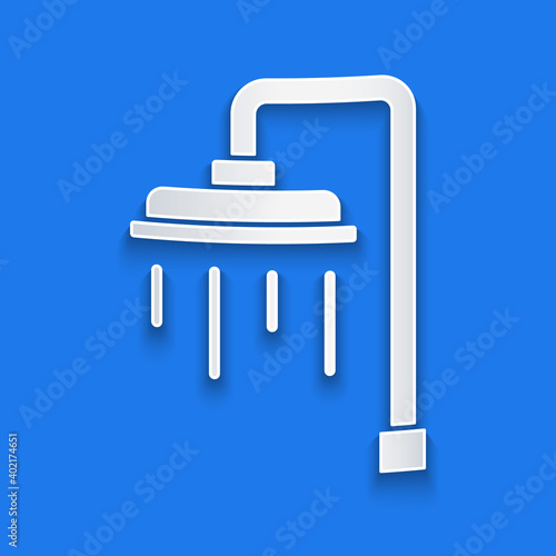Paper cut Shower head with water drops flowing icon isolated on blue background. Paper art style. Vector.