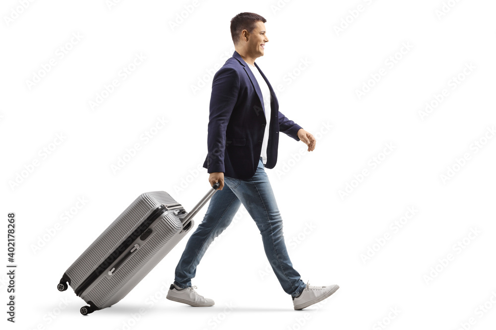 Full length profile shot of a young man smiling and walking with a suitcase Full length profile shot of a young man smiling and walking with a suitcase