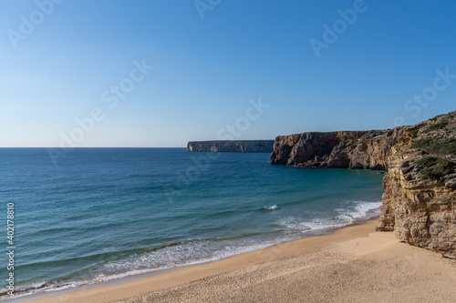 golden sand beach with wild tall cliffs and ocean