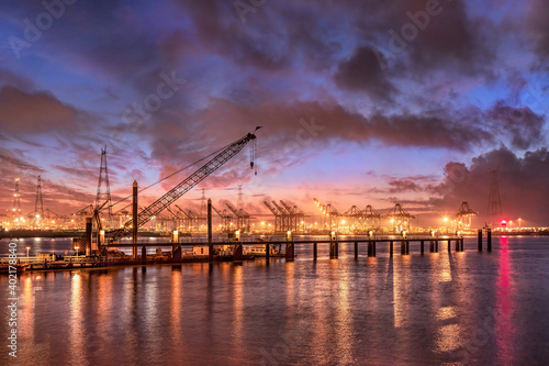 Industrial landscape at colorful sunset with pier and container terminal on the background  Port of Antwerp.