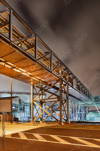 Night scene with pipeline overpass at petrochemical production plant, port of Antwerp, Belgium.