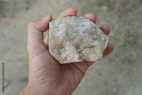 Raw quartzite rock stone in a hand. Quartzite is a nonfoliated metamorphic rock composed almost entirely of quartz.