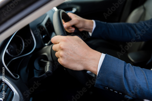 Cropped view of man in suit driving car on blurred background. © LIGHTFIELD STUDIOS