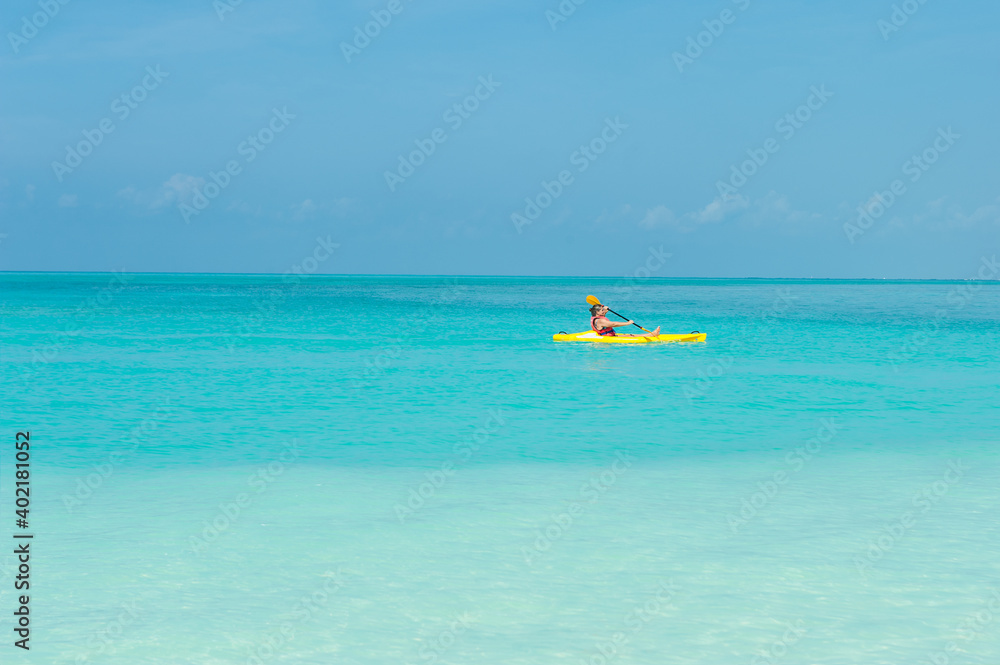 Elderly woman swimming on yellow canoe  boat and kayak in turquoise ocean